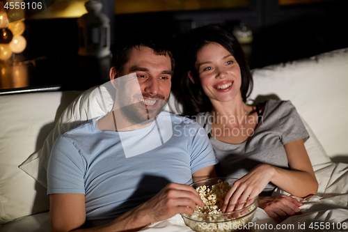 Image of couple with popcorn watching tv at night at home