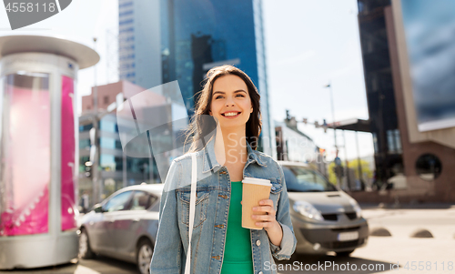 Image of happy young woman drinking coffee on city street