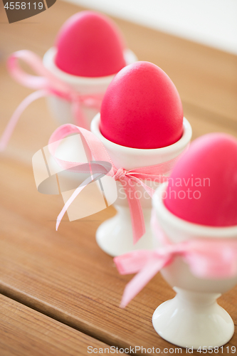 Image of pink colored easter eggs in holders on table