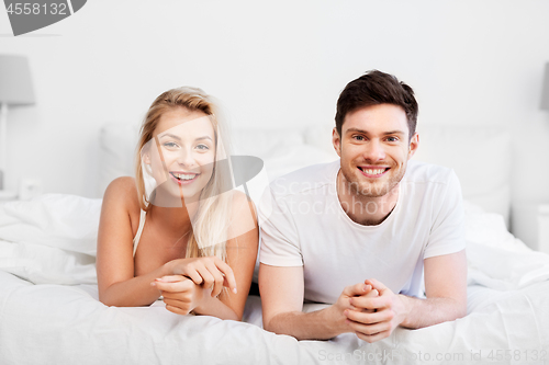 Image of happy couple lying in bed at home