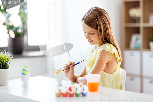 Image of happy girl coloring easter eggs at home