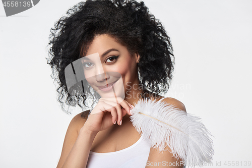 Image of Beautiful mixed race woman holding white ostrich feather