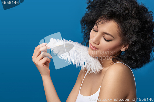 Image of Beautiful mixed race woman holding white ostrich feather