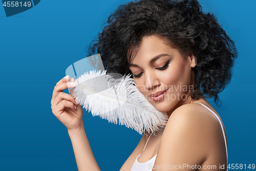 Image of Beautiful mixed race woman holding white ostrich feather