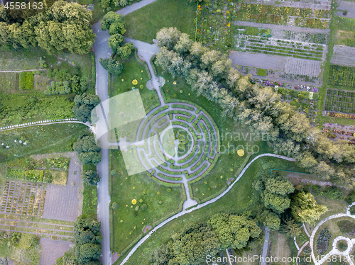 Image of Panoramic view from the drone to a part of botanical garden with with a labyrinth, trees, flower beds with flowers.