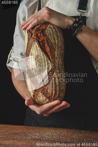 Image of Hands of man holding oval bread