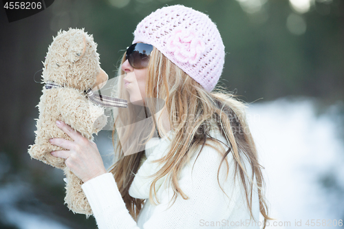 Image of Girl blowing kisses to scruffy teddy bear