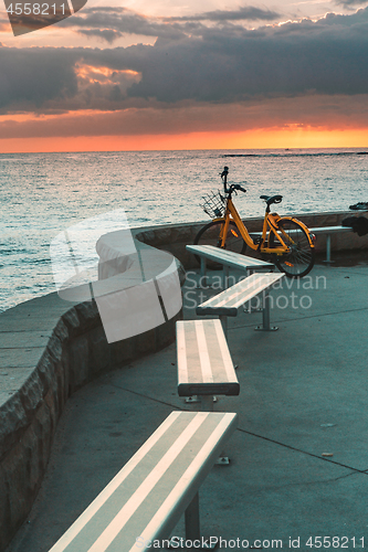 Image of Bicycle and empty bench seats overlooking ocean at sunrise