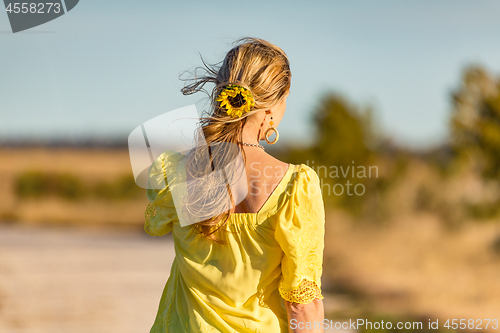 Image of Woman outdoors in sunshine sunflower in her wavy hair