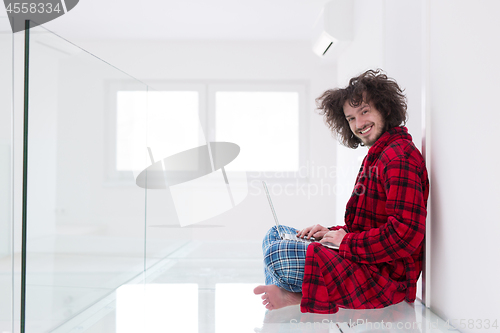 Image of young freelancer in bathrobe working from home