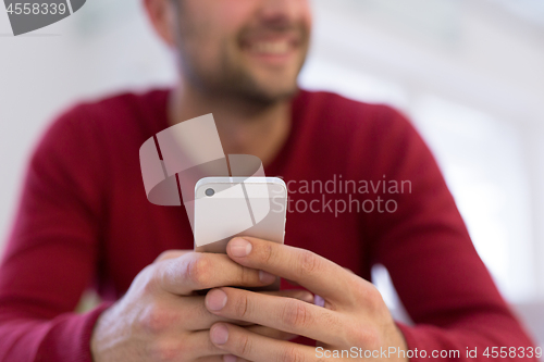 Image of young man using a mobile phone  at home