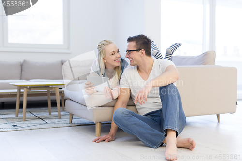 Image of couple relaxing at  home with tablet computers