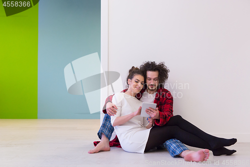 Image of Young Couple using digital tablet on the floor