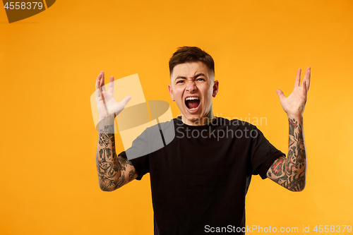 Image of The young emotional angry man screaming on studio background