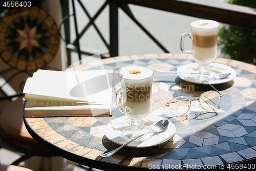 Image of Cup of coffee with book on table in room