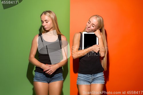 Image of Picture of two young happy women looking at the camera and holding laptop.