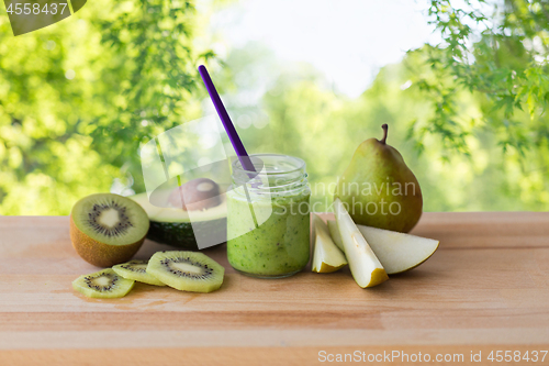 Image of jar with fruit puree or baby food on wooden board