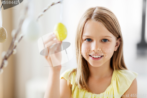 Image of girl decorating willow by easter eggs at home