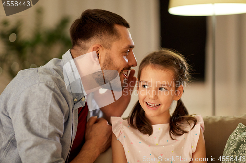 Image of happy father whispering secret to daughter at home