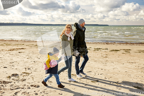 Image of happy family going to picnic on beach in autumn