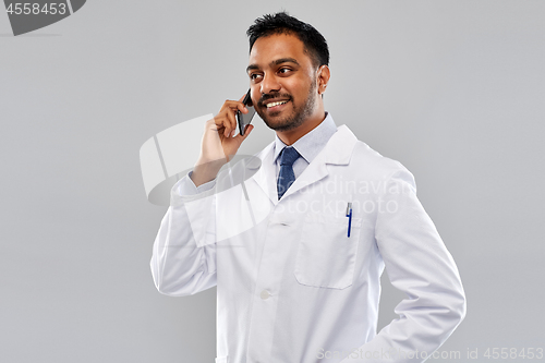 Image of smiling indian male doctor calling on smartphone