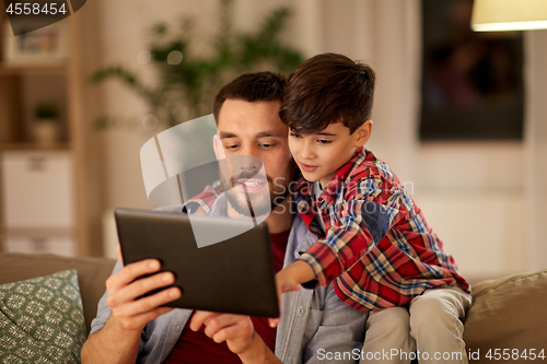 Image of father and son with tablet pc playing at home