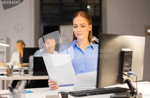 Image of businesswoman with papers working at night office