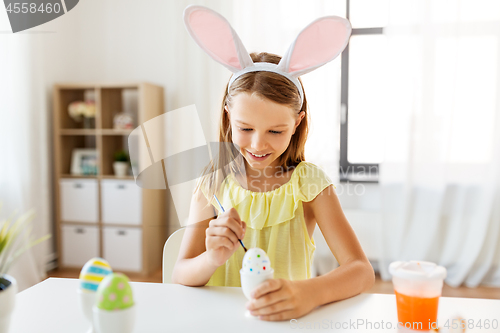 Image of happy girl coloring easter eggs at home