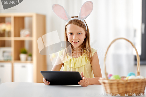 Image of happy girl with tablet pc and easter eggs at home