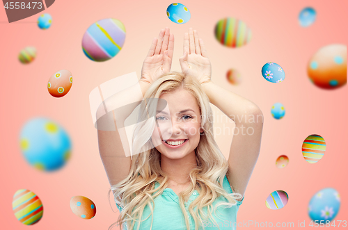 Image of happy smiling young woman making easter bunny ears