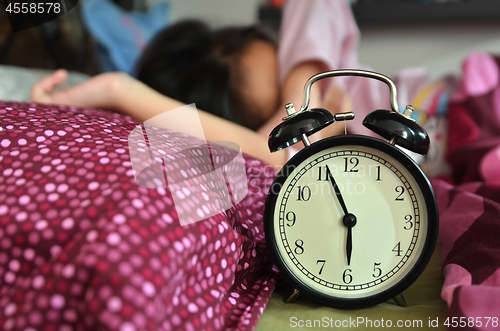 Image of Pretty girl sleeping on the background of a retro alarm clock