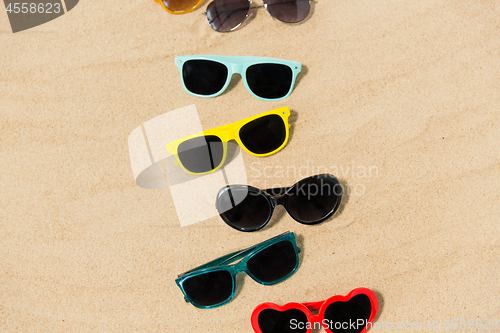 Image of different sunglasses on beach sand