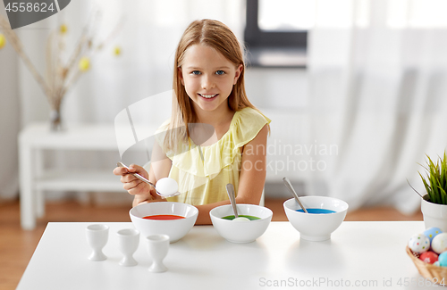 Image of girl coloring easter eggs by liquid dye at home