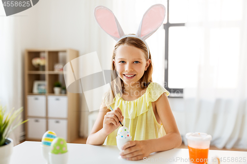 Image of happy girl coloring easter eggs at home