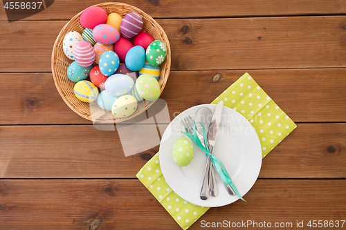 Image of easter eggs in basket, plates, cutlery and flowers