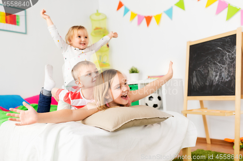 Image of happy little kids having fun in bed at home