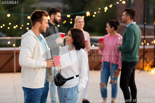 Image of friends with drinks in party cups at rooftop