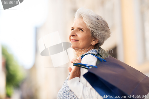 Image of senior woman with shopping bags in city