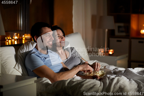 Image of couple with popcorn watching tv at night at home