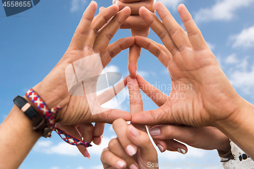 Image of hands of hippie friends making peace sign over sky