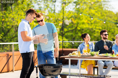 Image of happy friends grilling at bbq party on rooftop