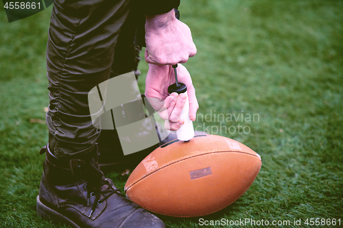 Image of man pumping air into american football ball