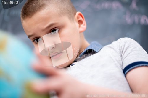 Image of boy using globe of earth in front of chalkboard