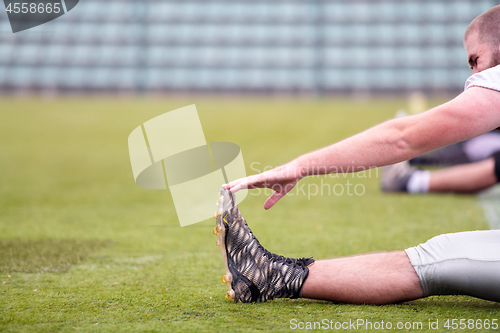 Image of american football players stretching and warming up