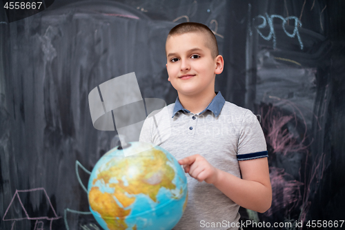 Image of boy using globe of earth in front of chalkboard