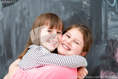 Image of little girls hugging in front of chalkboard