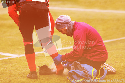 Image of Sports doctor using freezing spray while treating injured sportm