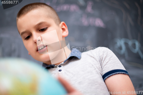 Image of boy using globe of earth in front of chalkboard