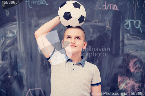 Image of happy boy holding a soccer ball on his head