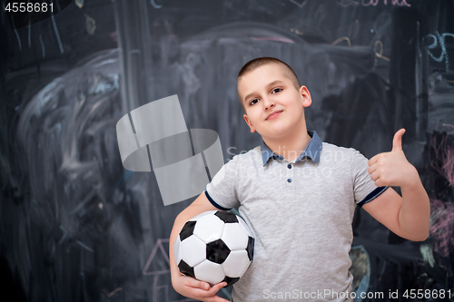 Image of happy boy holding a soccer ball in front of chalkboard